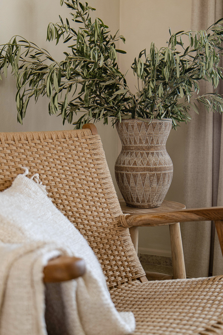 Rattan chair and olive branches in a carved vase – Studio Blanco interior design project